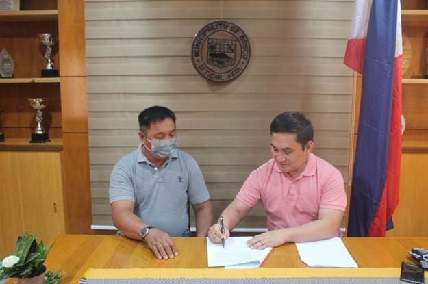 Mayor Demetrius Narag signs the MOU, sealing the partnership between Basco and Coca-Cola Beverages Philippines for PET plastic bottle collection and recycling . Mayor Narag is joined by Mr. Carlito Cari, Municipal Environment Officer of Basco. 